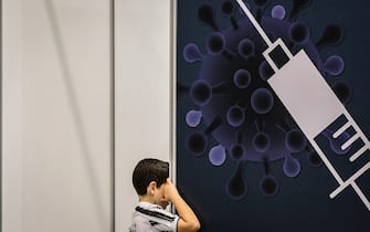 A child looks inside a booth at the Covid-19 vaccination centre of Parque das Nacoes in Lisbon on December 18, 2021, as Portugal started the vaccination of children from ages 5-11. - Europe stepped up vaccinations of children aged five to 11 against Covid-19, as the EU's health agency warned that immunisation alone would not stop the rapid rise of the Omicron variant of the virus. (Photo by PATRICIA DE MELO MOREIRA / AFP) (Photo by PATRICIA DE MELO MOREIRA/AFP via Getty Images)