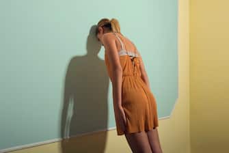 Rear View Of Sad Woman Leaning On Wall