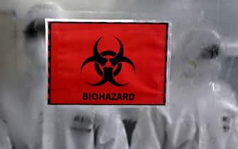Technicians wearing personal protective equipment (PPE) suits stand behind a biohazard sign inside a molecular laboratory facility set up to test for the monkeypox disease during its inauguration at the King Institute in Chennai on July 28, 2022. (Photo by Arun SANKAR / AFP) (Photo by ARUN SANKAR/AFP via Getty Images)