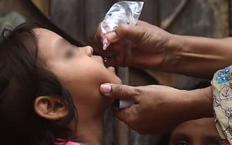 A health worker administers polio drops to a child during a polio vaccination campaign in Karachi on August 15, 2022. (Photo by Rizwan TABASSUM / AFP) (Photo by RIZWAN TABASSUM/AFP via Getty Images)