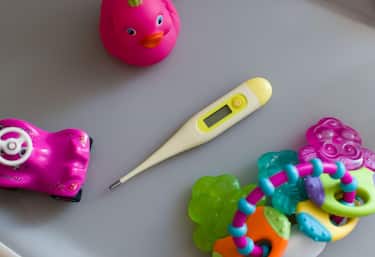Thermometer with toys on gray background. Temperature measuring in cold and flu virus time. Children healthcare concept