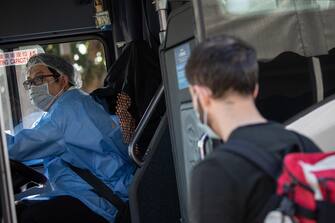 epa08365857 An air traveler (R), boards a shuttle bus at Asia World Expo after being tested for COVID-19 in Hong Kong, China, 16 April 2020. A Hong Kong government requirement forces all air passengers arriving at Hong Kong to be tested for the SARS-CoV-2 coronavirus, which causes the COVID-19 disease, at Asia World Expo near the airport.  EPA/JEROME FAVRE