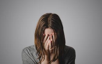 salute mentale Woman covers face in hands. Concept of despair, depression, loss or mental condition