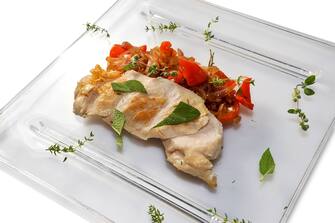 Pollo chicken breast with peppers and onions after sous vide cooking on glass dish on white background