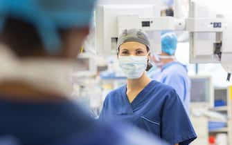 Female doctor wearing surgical cap and mask looking at camera