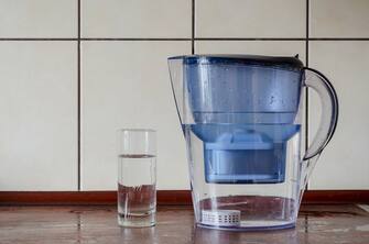 Water filter jug Ã¢Â Â Ã¢Â Â with silicon cartridge inside on the kitchen counter. Silicon cartridge for saturation of liquid with minerals. Plastic jug and  glass of purified water. Drink water.
