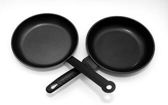 Empty black non stick stainless steel frying pans isolated on white background