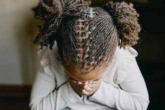 Little African American Girl with Beautiful Pigtail Locs while covering her face with her hands.