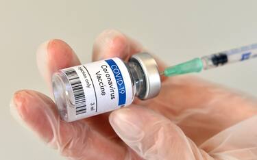 Coronavirus vaccine vial container in hand on white background. Close-up view. Coronavirus vaccine bottle.