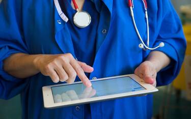 A doctor on a ward checks a patients' records on an Ipad