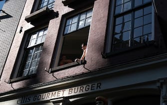 AMSTERDAM, NETHERLANDS - MAY 9: People sit inside their house as they open a window above a closed burger shop on May 9, 2020 in Amsterdam, Netherlands. (Photo by Yuriko Nakao/Getty Images)