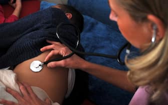 Una donna ascolta il respiro di un bambino con un fonendoscopio