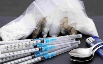 Drug injection syringe and cooked heroin in a bag on black table