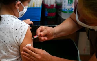 A medical worker applies a flu vaccine to a girl in Asuncion, on June 9, 2020, amid the COVID-19 coronavirus pandemic. - Health authorities in Paraguay are encouraging people over 60 and children to be vaccinated against the flu, also those who suffer respiratory diseases, to reduce complications of those who might contract the virus. (Photo by NORBERTO DUARTE / AFP) (Photo by NORBERTO DUARTE/AFP via Getty Images)