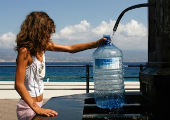 A girl fills a water bottle from a fountain in Messina on August 19, 2009. A heatwave stifled Italy today, with temperatures up to 41 degrees Celsius (106 Fahrenheit) and civil protection authorities issuing warnings for several cities including Rome and Milan. AFP PHOTO / MARCELLO PATERNOSTRO (Photo credit should read MARCELLO PATERNOSTRO/AFP via Getty Images)