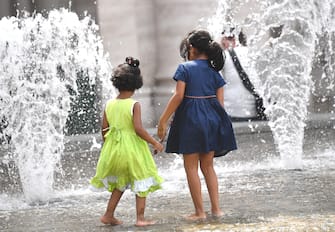 Due bambine giocano con le fontane di piazza De Ferrari. Genova, 31 luglio 2019. 
ANSA/LUCA ZENNARO