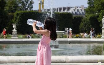 A girl drinks water from a bottle near a fountain in the Tuileries Garden in Paris on July 2, 2015, as a heatwave sweeps through Europe. AFP PHOTO / MIGUEL MEDINA