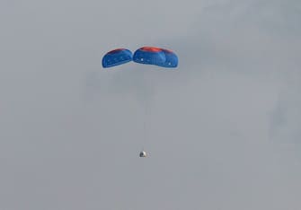 VAN HORN, TEXAS - JULY 20: Blue Originâ  s New Shepard crew capsule descends on the end of its parachute system carrying Jeff Bezos along with his brother Mark Bezos, 18-year-old Oliver Daemen, and 82-year-old Wally Funk on July 20, 2021 in Van Horn, Texas. Mr. Bezos and the crew are riding in the first human spaceflight for the company.   (Photo by Joe Raedle/Getty Images)