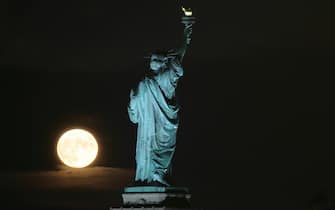 JERSEY CITY, NJ - AUGUST 22: The full Sturgeon Blue Moon rises next to the Statue of Liberty in New York City on August 22, 2021 as seen from Jersey City, New Jersey. (Photo by Gary Hershorn/Getty Images)