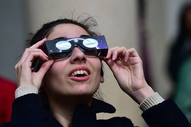 A woman uses special protective glasses to watch a partial solar eclipse of the sun at piazza del Duomo in Milan on March 20, 2015.  AFP PHOTO / GIUSEPPE CACACE        (Photo credit should read GIUSEPPE CACACE/AFP via Getty Images)