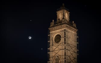 Venus and Jupiter planets in conjunction with a crescent moon rise behind municipality tower in Piazza Palazzo square in LAquila (Italy) on february 22, 2023.  (Photo by Lorenzo Di Cola/NurPhoto via Getty Images)