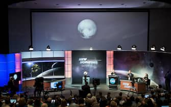 480659406 People look at an early image of Pluto taken by NASA's New Horizons probe as the craft makes its closest fly-by of the dwarf planet at the Johns Hopkins University Applied Physics Laboratory July 14, 2015 in Laurel, Maryland. The unmanned NASA spacecraft whizzed by Pluto on July 14, making its closest approach in the climax of a decade-long journey to explore the dwarf planet for the first time, the US space agency said. Moving faster than any spacecraft ever built -- at a speed of about 30,800 miles per hour (49,570 kph) -- the flyby happened at 7:49 am (1149 GMT), with the probe running on auto-pilot. It was to pass by Pluto at a distance of 7,767 miles (12,500 kilometers). AFP PHOTO/BRENDAN SMIALOWSKI (Photo credit should read BRENDAN SMIALOWSKI/AFP via Getty Images)