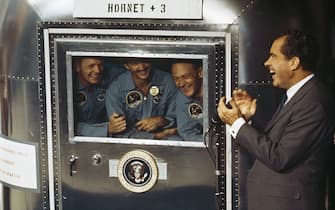 24th July 1969:  From left to right, Neil Armstrong, Michael Collins and Edwin 'Buzz' Aldrin Jnr, the crew of the historic Apollo 11 moon landing mission are subjected to a period of quarantine upon their return to earth. Through the window of their Mobile Quarantine Facility, they hold a conversation with President Richard Nixon (1913 - 1994).  (Photo by MPI/Getty Images)