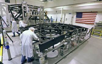 Engineers work on the graphite super structure of the science module section, left, and the mirror super structure, right, of the "James Webb Telescope", the replacement for the Hubble Telescope, at ATK's Space Components Division on April 23, 2013 in Magna, Utah.  The 8 billion dollar telescope project will be launched into space in 2018 and will be 100 time more powerful then the current Hubble telescope. Bloomberg News/George Frey