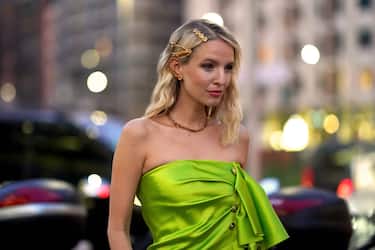 MILAN, ITALY - FEBRUARY 21: Leonie Hanne wears a neon green/yellow lustrous off-shoulder dress, a golden necklace, hair pins,  outside Versace, during Milan Fashion Week Fall/Winter 2020-2021 on February 21, 2020 in Milan, Italy. (Photo by Edward Berthelot/Getty Images)