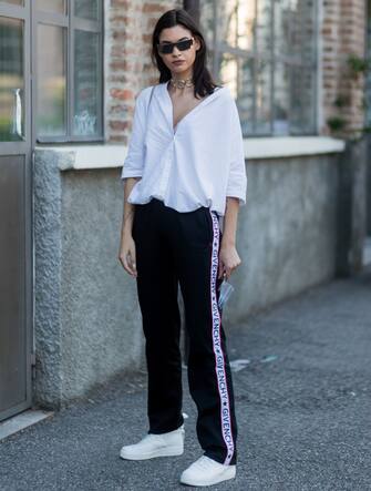 697911270 MILAN, ITALY - JUNE 19: A guest wearing a white button shirt and a Givenchy jogger pants is seen outside Malibu 1992 during Milan Men's Fashion Week Spring/Summer 2018 on June 19, 2017 in Milan, Italy. (Photo by Christian Vierig/Getty Images)
