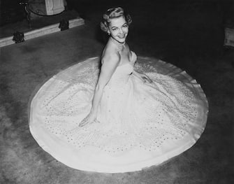 American actress and singer Vivian Blaine (1921 - 1995), star of the musical 'Guys and Dolls', tries on her dress for the Royal Command Performance at the London Coliseum, 30th October 1953. The dress is made of white georgette over white taffeta, decorated with pearl beads. (Photo by Reg Burkett/Keystone/Hulton Archive/Getty Images)
