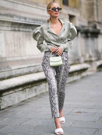 PARIS, FRANCE - SEPTEMBER 25: Leonie Hanne wears sunglasses, a lustrous light green wrap shirt with puff long sleeves and a plunging neckline, a light green handbag,  grey python pattern pants, white quilted mules, outside Unravel Project, during Paris Fashion Week - Womenswear Spring Summer 2020, on September 25, 2019 in Paris, France. (Photo by Edward Berthelot/Getty Images)