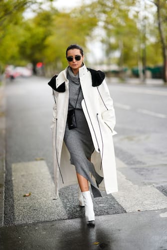 PARIS, FRANCE - OCTOBER 06: Julia Comil wears sunglasses, a white log coat with black shoulder pads, a gray wool turtleneck dress, a black leather small bag, white shoes, outside Louis Vuitton, during Paris Fashion Week - Womenswear Spring Summer 2021, on October 06, 2020 in Paris, France. (Photo by Edward Berthelot/Getty Images)