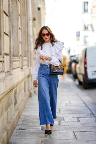 PARIS, FRANCE - SEPTEMBER 15: Therese HellstrÃ¶m wears red Celine sunglasses, a white shirt / blouse from H&M with large ruffled collar, a black leather Karl Lagerfeld bag with a chain and brown leopard print, blue denim flared jeans from Zara, pointy shoes with bow tie from Custommade, on September 15, 2020 in Paris, France. (Photo by Edward Berthelot/Getty Images)