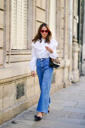 PARIS, FRANCE - SEPTEMBER 15: Therese HellstrÃ¶m wears red Celine sunglasses, a white shirt / blouse from H&M with large ruffled collar, a black leather Karl Lagerfeld bag with a chain and brown leopard print, blue denim flared jeans from Zara, pointy shoes with bow tie from Custommade, on September 15, 2020 in Paris, France. (Photo by Edward Berthelot/Getty Images)