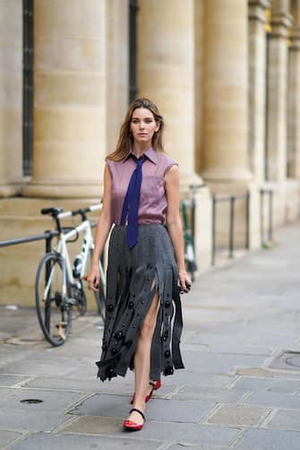 PARIS, FRANCE - OCTOBER 12: Natalia Verza wears a total Prada look: a purple sleeveless shirt, a blue tie, a gray fringed-edge wool midi skirt with embroidery, red leather shiny flat shoes, a mini Prada bag, on October 12, 2020 in Paris, France. (Photo by Edward Berthelot/Getty Images)