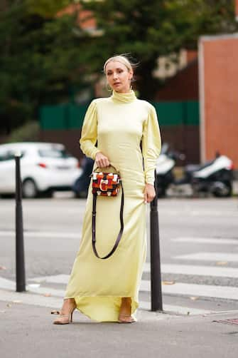 PARIS, FRANCE - SEPTEMBER 26: Justyna Czerniak wears earrings, a light yellow hi-neck puff sleeves asymmetric long dress, a Chloe orange, brown and white bag, mesh heels, outside Ann Demeulemeester, during Paris Fashion Week - Womenswear Spring Summer 2020 on September 26, 2019 in Paris, France. (Photo by Edward Berthelot/Getty Images)