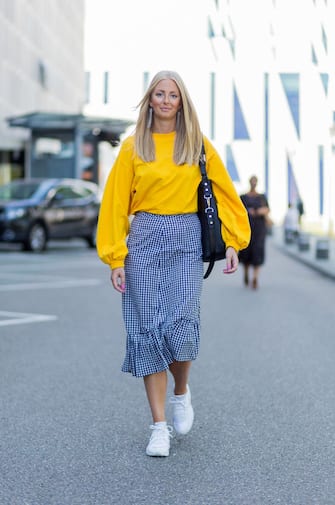 COPENHAGEN, DENMARK - AUGUST 09: A guest wearing yellow sweater, grey plaid skirt, sneakers on August 09, 2017 in Copenhagen, Denmark. (Photo by Christian Vierig/Getty Images)