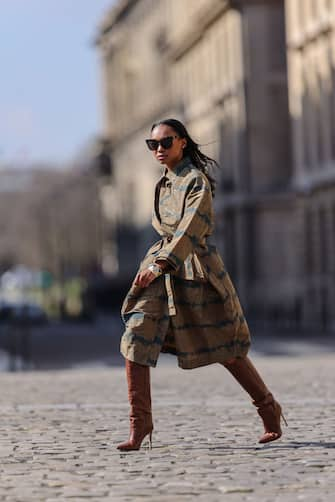 PARIS, FRANCE - MARCH 19: Emilie Joseph @in_fashionwetrust wears sunglasses, a trench oversized sculptural tie and dye kaki with stripes and military patterns from Henrik Vibskov, a spiked metallic bracelet, brown leather high heels crocodile pattern pointy boots from Paris Texas, on March 19, 2021 in Paris, France. (Photo by Edward Berthelot/Getty Images)