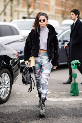 PARIS, FRANCE - FEBRUARY 28: A guest wears sunglasses, a black coat with fluffy parts, a gray wool turtleneck crop top, military camouflage pattern printed gray and green leggings, boots, a leather bag, outside Balmain, during Paris Fashion Week - Womenswear Fall/Winter 2020/2021, on February 28, 2020 in Paris, France. (Photo by Edward Berthelot/Getty Images)