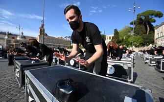 Entertainment workers bang on equipment cases during a flashmob performance called by the 'Bauli in Piazza' movement to protest against restrictions and closures linked to the coronavirus Covid-19 pandemic, in central Rome's square of Piazza del Popolo on April 17, 2021. (Photo by Vincenzo PINTO / AFP) (Photo by VINCENZO PINTO/AFP via Getty Images)