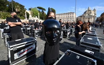 A protester poses with a mask as entertainment workers perform a flashmob during a demonstration called by the "Bauli in Piazza" movement to protest against restrictions and closures linked to the coronavirus pandemic, in central Rome's square of Piazza del Popolo on April 17, 2021. (Photo by Vincenzo PINTO / AFP) (Photo by VINCENZO PINTO/AFP via Getty Images)