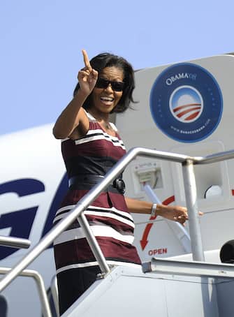 Michelle Obama, wife of US Democratic presidential candidate Illinois Senator Barack Obama signals to the press that she will be right back as she goes back onto the campaign plane after arrival at Detroit Metropolitan International airport in Detroit, Michigan, September 28, 2008.   AFP PHOTO/Emmanuel Dunand (Photo credit should read EMMANUEL DUNAND/AFP via Getty Images)