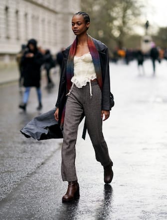LONDON, ENGLAND - FEBRUARY 16: A model wears a black leather jacket a colored scarf, gray pants, black leather shoes, during London Fashion Week Fall Winter 2020 on February 16, 2020 in London, England. (Photo by Edward Berthelot/Getty Images)