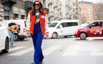 Eleonora Carisi wears an orange Reebok embroidered bomber varsity jacket, a graphic print t-shirt, and blue Korsun high-waisted trousers at the Antonio Marras show during the Milan Fashion Week Fall/Winter 2016/17 on February 27, 2016 in Milan, Italy.