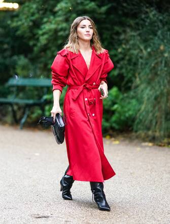 PARIS, FRANCE - SEPTEMBER 29: A guest wears a red dress / long trench coat, black pointy leather boots, a black leather bag, outside Koche, during Paris Fashion Week - Womenswear Spring Summer 2021 on September 29, 2020 in Paris, France. (Photo by Edward Berthelot/Getty Images)