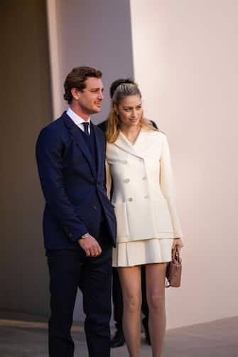 PARIS, FRANCE - JANUARY 24: Pierre Casiraghi (L) wears a white shirt, a navy blue tie, a navy blue wool V-neck pullover, a navy blue blazer jacket, navy blue suit pants;  Beatrice Borromeo (R) wears earrings, a gold chain pendant necklace, a white t-shirt, a white latte buttoned jacket, a matching white latte pleated / accordion short skirt, a brown shiny leather Lady D-Lite hand bag from Dior, outside Dior during Paris Fashion Week - Haute Couture Spring / Summer 2022, on January 24, 2022 in Paris, France.  (Photo by Edward Berthelot / Getty Images)