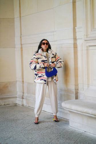 PARIS, FRANCE - FEBRUARY 23: Gabriella Berdugo wears sunglasses, a white mesh lavalliere, a printed white blue and pink zebra pattern winter puffer coat from Moncler, beige jogger sportswear sweatpants from Moncler, colored sling back pointed shoes from Roger Vivier, a blue bag from Coperni, on February 23, 2021 in Paris, France.  (Photo by Edward Berthelot / Getty Images)