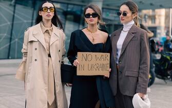 MILAN, ITALY - FEBRUARY 24: Three guests pose ahead of the Max Mara fashion show with a sign against war in Ukraine during the Milan Fashion Week Fall/Winter 2022/2023 on February 24, 2022 in Milan, Italy. (Photo by Valentina Frugiuele/Getty Images)