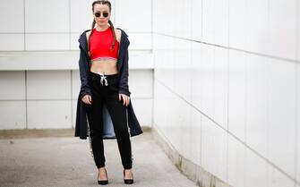 PARIS, FRANCE - MARCH 19:  Amelie Lloyd, fashion blogger, wears Jennyfer pants with the printed inscription "Not Your BAE", a Jennyfer red sleeveless bare belly shirt, sunglasses, a Zara blue trench coat, and has braided hair, on March 19, 2017 in Paris, France.  (Photo by Edward Berthelot/Getty Images)
